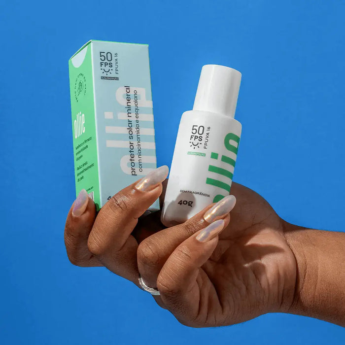 Mão com unhas feitas segurando a embalagem e caixa do proetor solar mineral fluido FPS 50 da Ollie.